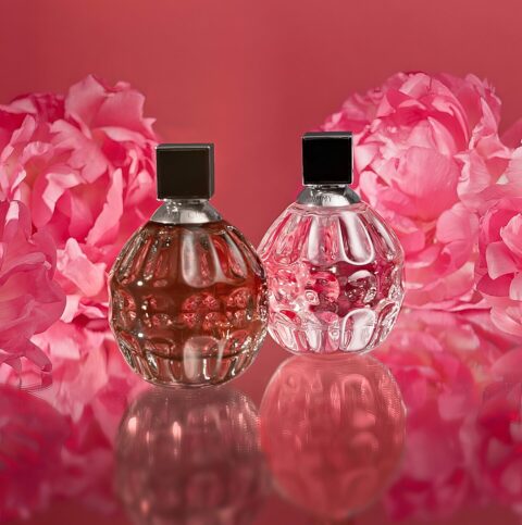 2 parfums Jimmy Choo sur fond rose avec des fleurs en arrière plan
